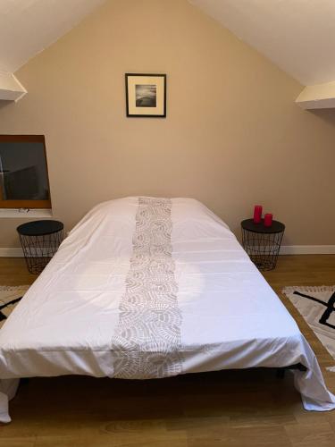 a large white bed in a room with two tables at Maison à la campagne in Lupersat
