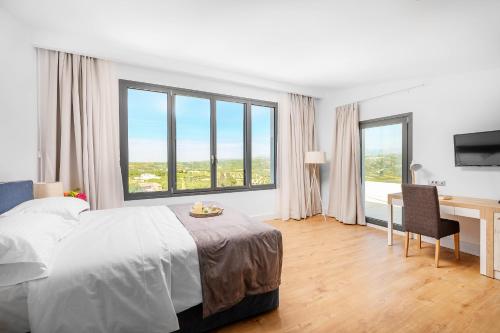 a bedroom with a bed and a desk and windows at 5star Villa Harmony w heated pool, Gym, Spa, Sauna in Skalánion