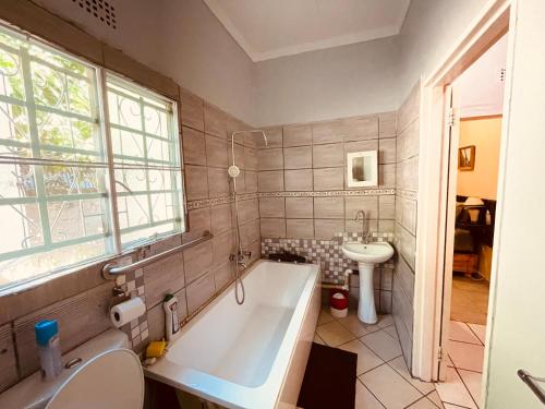 a bathroom with a tub and a sink at Abrama Bed And Breakfast in Francistown
