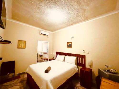 1 dormitorio con 1 cama con colcha blanca en Abrama Bed And Breakfast en Francistown