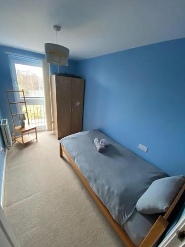 Fabulous 3 Bedroom Flat في إدنبرة: غرفة نوم زرقاء مع سرير بجدار ازرق