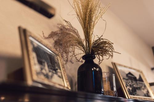 a vase with grass in it on a table with pictures at Seehotel Einwaller - adults only in Pertisau