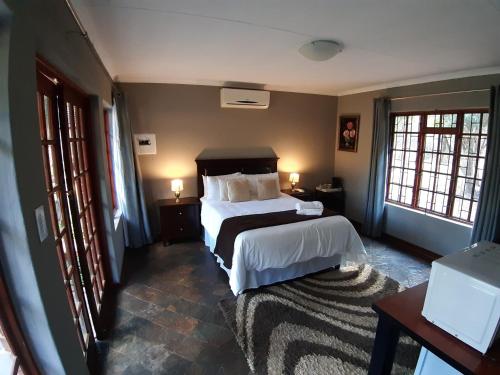 1 dormitorio con 1 cama y 2 ventanas en Tapologo Lodge, en Zeerust