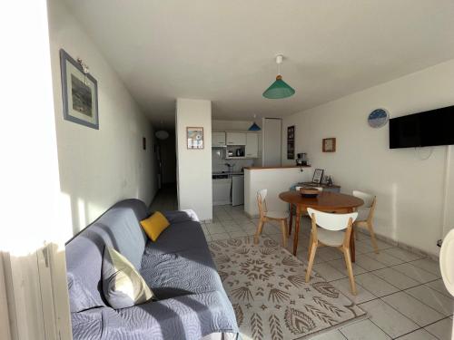 un salon avec un canapé bleu et une table dans l'établissement LA GOELETTE, à Fort-Mahon-Plage