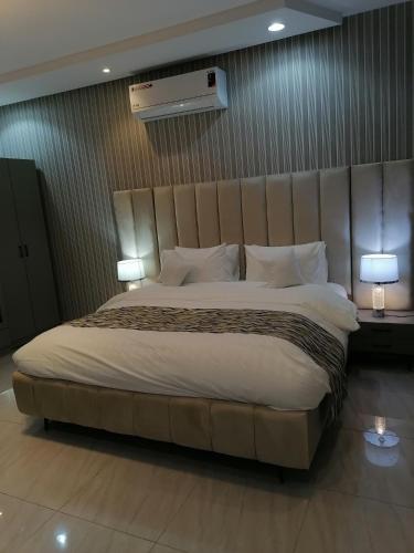 شقة فاخرة حي الرمال في الرياض: سرير كبير في غرفة الفندق مع مصباحين