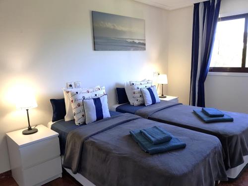 sypialnia z 2 łóżkami i niebieską pościelą w obiekcie Excellent T2 apartment with pools 400m Falesia beach w Albufeirze