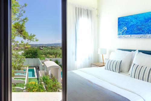 Romantic, homely Villa Aura w heated pool في Skalánion: غرفة نوم مع سرير وإطلالة على المحيط