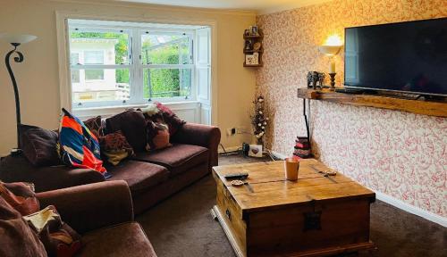 a living room with a couch and a tv at Country home near the airport in Edinburgh