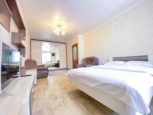 a bedroom with a large bed and a living room at 1-кімн Простора квартира в НОВОМУ будинку в самому серці Полтави in Poltava