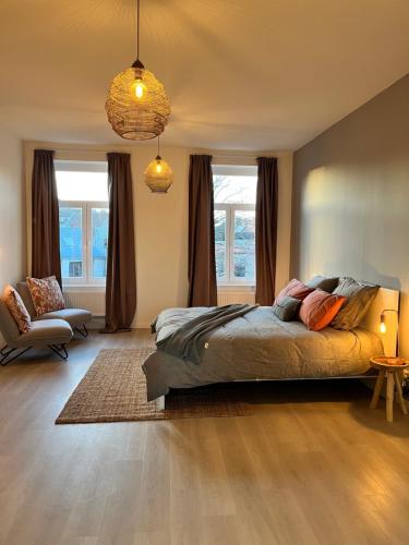 a bedroom with a bed and a chair and windows at Holiday Home La Petite Maison in Ghent