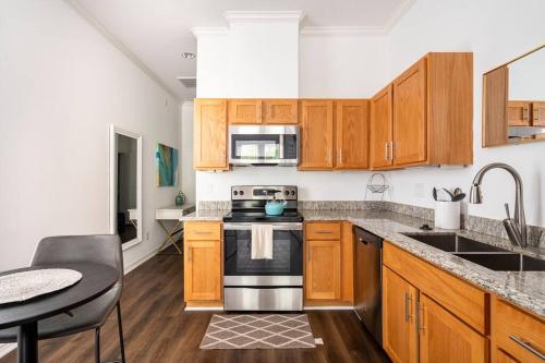 a kitchen with wooden cabinets and a stove top oven at Chic Urban Living Minutes from I-45 and I-610 #A in Houston