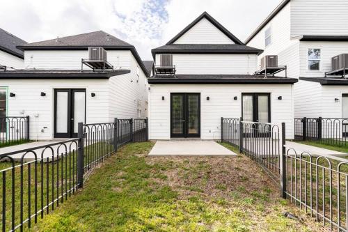 a white house with a fence in front of it at Chic Urban Living Minutes from I-45 and I-610 #A in Houston