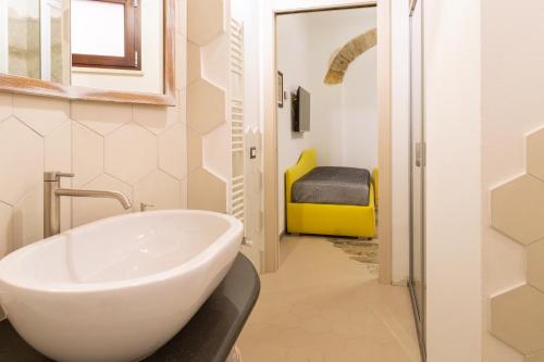 een badkamer met een witte wastafel en een gele stoel bij Trigu & Mangoni in Cagliari