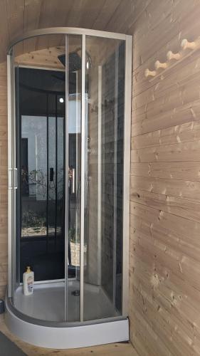 - une douche en verre dans une chambre dotée d'un mur en bois dans l'établissement Gîtes insolites proche Nancy, à Marbache