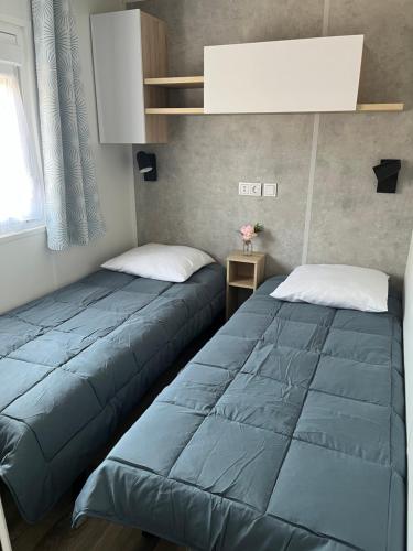 dwa łóżka ustawione obok siebie w pokoju w obiekcie MH 3 chambres, camping Les Dunes de Contis, Landes w mieście Saint-Julien-en-Born