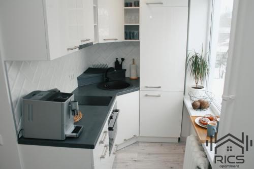 a white kitchen with a sink and a microwave at Rics Apartment in Valga