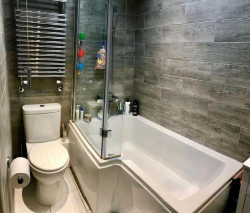 a bathroom with a shower and a toilet and a tub at 2 Priests Mews in Swanage