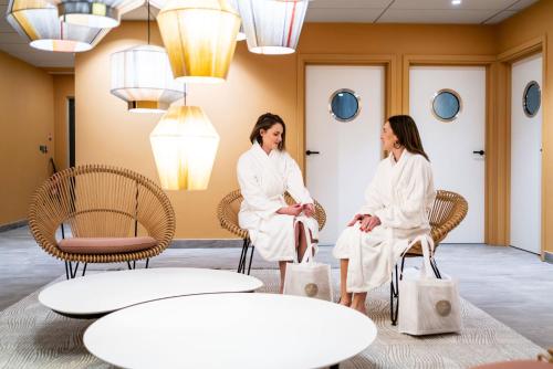 two women in white robes sitting in chairs in a room at Hôtel Roz Marine Thalasso Resort in Perros-Guirec
