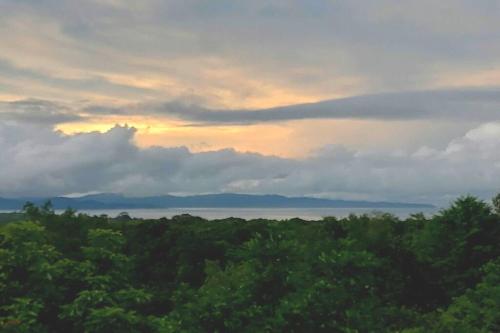 a sunset over a forest of trees with the sky at CasaBravaVentura Jungle Ecofarm in Santa Catalina