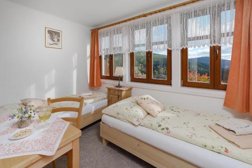 1 dormitorio con 2 camas, mesa y ventanas en U Novotných, en Špindlerův Mlýn