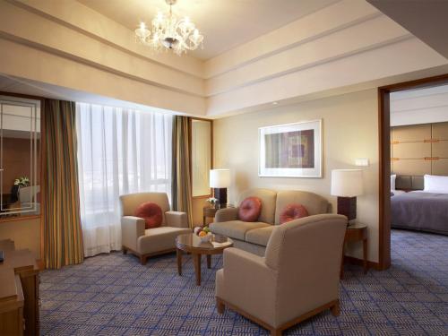 a hotel room with a couch and chairs and a bed at Shangri-La Baotou in Baotou