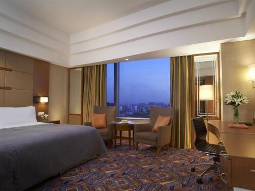 a hotel room with a bed and a desk and a window at Shangri-La Baotou in Baotou