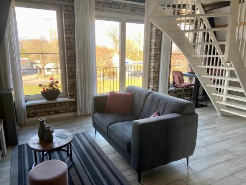 uma sala de estar com um sofá e uma escada em Slapen an de Veenvaart em Nieuw-Amsterdam
