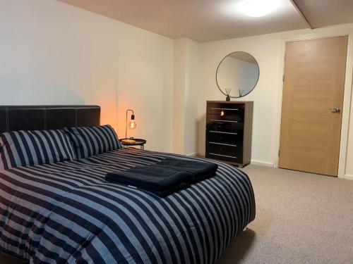 um quarto com uma cama com um espelho e uma cómoda em Apartment in Old Trafford em Manchester