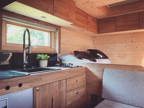 una cocina con fregadero y una cama en una habitación en Zinipi Lodge am Oldtimer auf Demeterhof Michlbauer, en Ursensollen