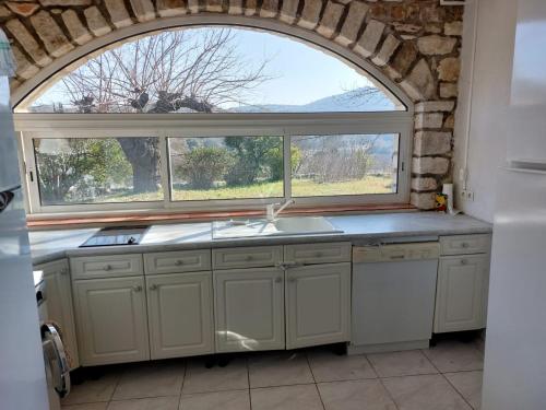 una cocina con una ventana abovedada y un fregadero en Le Gite, en Labastide-de-Virac