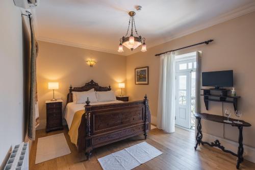 a bedroom with a bed and a television and a chandelier at Quinta do Outeiro in Resende