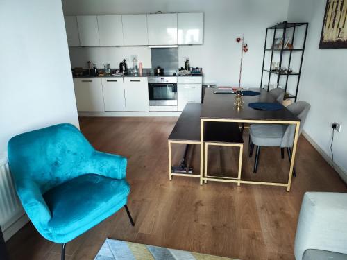 a living room with a blue chair and a table at Spacious & Serene Stay in London in Forest Hill