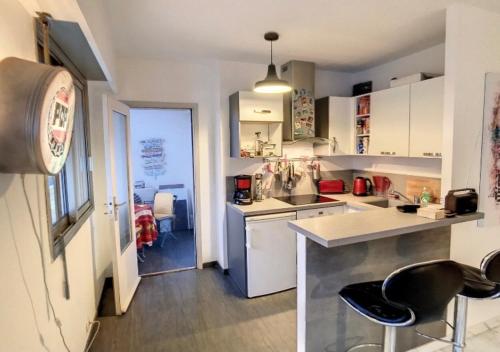 - une cuisine avec des placards blancs et des tabourets noirs dans l'établissement Superbe Studio tout équipé/Proche mer et commodité, à Saint-Laurent-du-Var