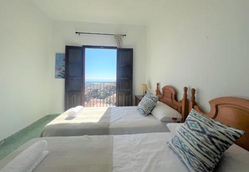 Duas camas num quarto com uma janela em BnS - Casa La Prensa - Alpujarra em Sorvilán