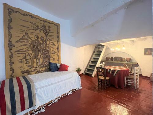 um quarto com uma cama, uma mesa e uma escada em BnS - Casa La Prensa - Alpujarra em Sorvilán