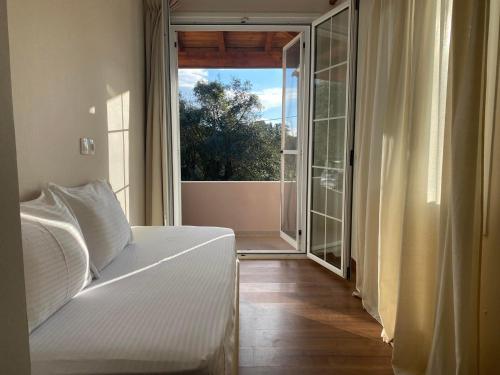 ein Schlafzimmer mit einem weißen Bett und einem großen Fenster in der Unterkunft Paris Apartment in Doukádes