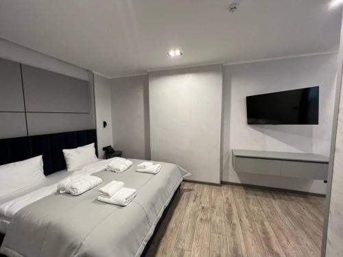 a bedroom with a large white bed with a flat screen tv at Rest&Ski Spa Resort in Bukovel