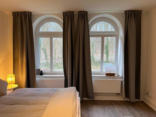 a bedroom with a bed and two windows at Ferienwohnung in Bad Bramstedt in Bad Bramstedt