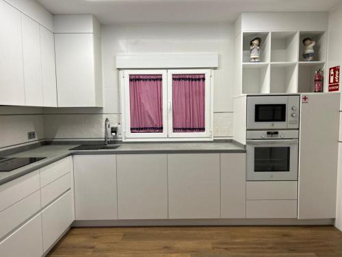 uma cozinha branca com armários brancos e uma janela em Casa La Rosada em Garray