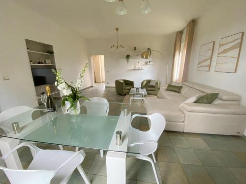 a living room with a glass table and white chairs at Villa Boeddu, relax tra mare e campagna in Alghero
