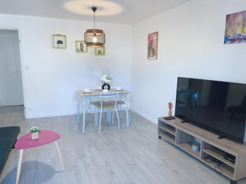 a living room with a large television and a table at Apt 67m2 hyper centre: 2 chambres, cuisine TV wifi in Fontenay-le-Comte