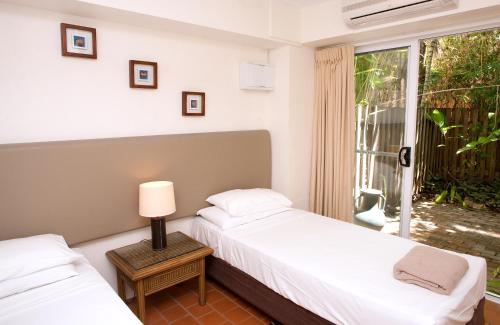 zwei Betten in einem Zimmer mit Fenster in der Unterkunft Coral Sea Villas in Port Douglas