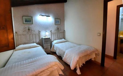 a bedroom with two beds with white sheets at La Casina de la Huerta in Llanes