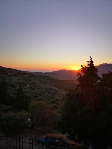 a sunset over a field with a fence and trees at Casa Opuntia in Pappayiannádhes