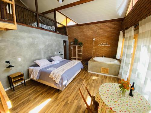 a bedroom with a bed and a tub and a table at Chalé Jacarandá - Hidro - Wifi e mais in Sapucaí-Mirim