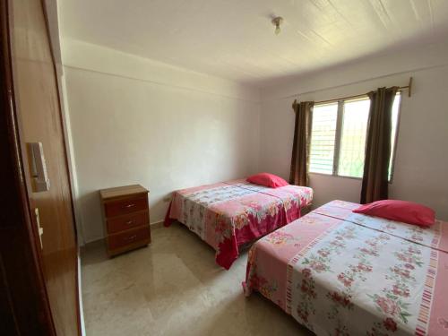 a bedroom with two beds and a window at Hostel Casa Verde, Tela Atlantida. in Tela