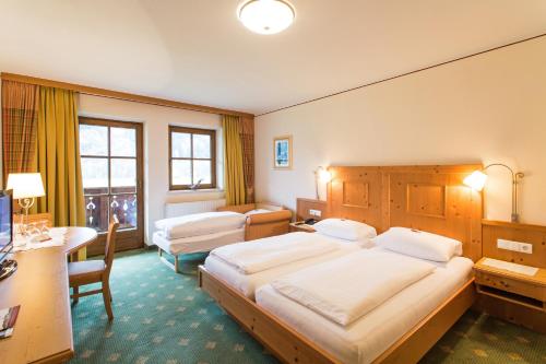 a hotel room with two beds and a desk at Alpenrast Tyrol in Mils bei Imst