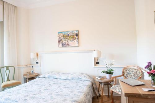 a bedroom with a bed and a desk with a laptop at Hotel Royal in Stresa