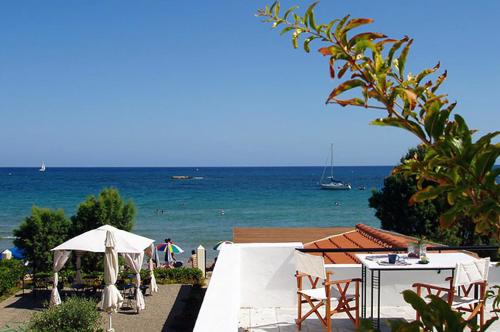 a beach with tables and umbrellas and the ocean at Talgo Suites in Stalida