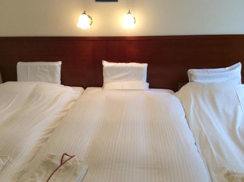 two beds in a room with white sheets at Hotel Sun Queen in Naha